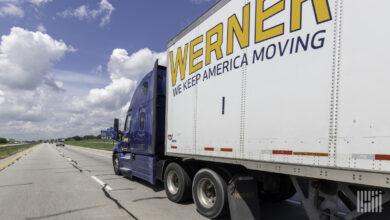 A blue Werner tractor pulling a white Werner trailer on the highway