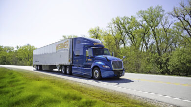 A blue Werner tractor on the highway pulling a trailer