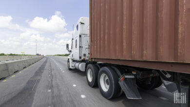 A tractor pulling an ocean container on a highway.