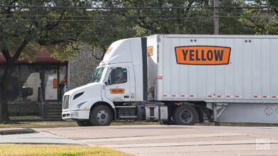 A Yellow tractor pulling a Yellow trailer on a side street