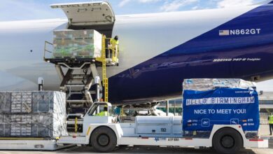 A hydraulic lift platform carries a pallet of cargo down from a large cargo jet.