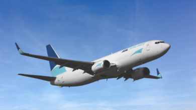 A white ASL cargo jet with a blue tail flying high against a blue sky.