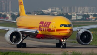 A mustard-yellow DHL cargo jet rolls down the runway.