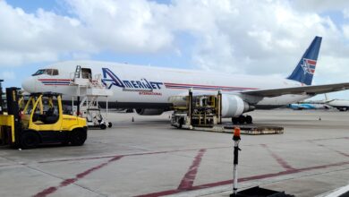 A light-blue tailed Amerijet freighter on the tarmac with its cargo door open on a sunny day.