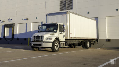 A white last-mile truck backed up to a warehouse