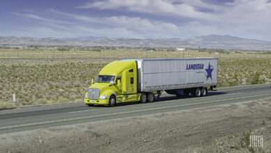 A yellow tractor pulling a white Landstar trailer