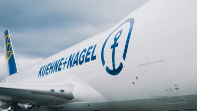 Close of large airplane with blue Kuehne+Nagel logo on white fuselage.