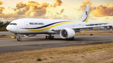 A white MSC Air Cargo plane with yellow and black stripe with a fiery orange sky in the background.