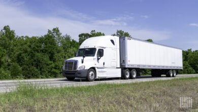 A white tractor pulling a white trailer on a highway