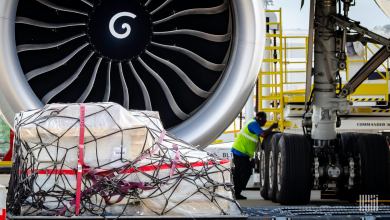 A pallet of cargo in front of a large jet engine on an aircraft.