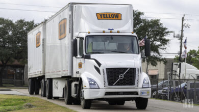 A Yellow tractor pulling two Yellow LTL trailers