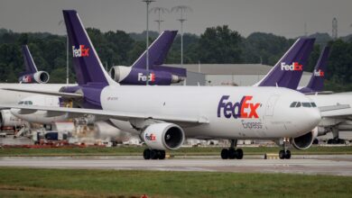 Several purple-tailed FedEx planes at an airport.