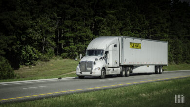 A white tractor pulling a white J.B. Hunt trailer on a highway