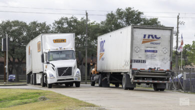 A Yellow truck and a YRC trucking passing each other at a terminal in Houston