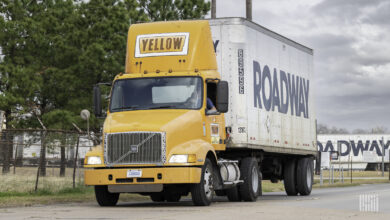 A Yellow truck with a Roadway trailer leaving a terminal in Houston