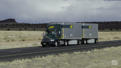 A green ABF tractor pulling two pup trailers on the highway