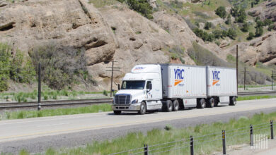 A white YRC tractor with two YRC LTL trailers