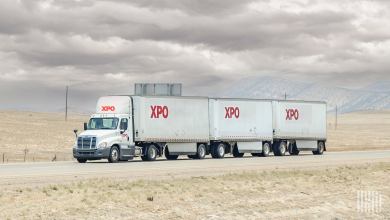 An XPO tractor pulling three XPO trailers on the highway