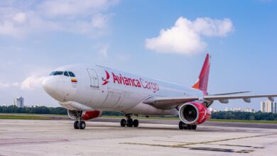 A red-and-white Avianca Cargo jet on the tarmac with a blue sky in the background and spotty white clouds.