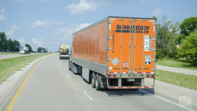 An orange Schneider trailer being pulled on a highway