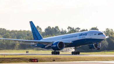 A blue-and-white Silk Way West Airlines cargo jet touches down on a runway.