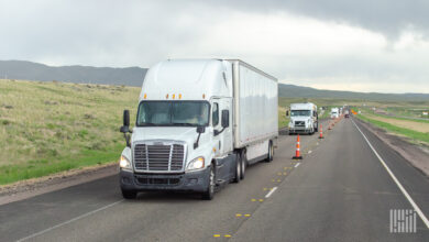 a white tractor pulling a white trailer on a highway