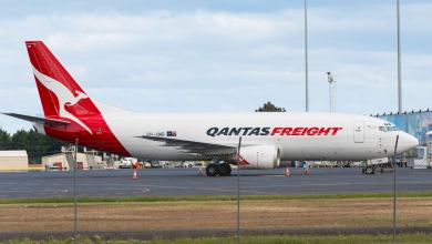 Red-tailed Qantas Freight jet parked at an airport by itself.