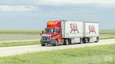 A red Saia tractor pulling two white Saia pup trailers