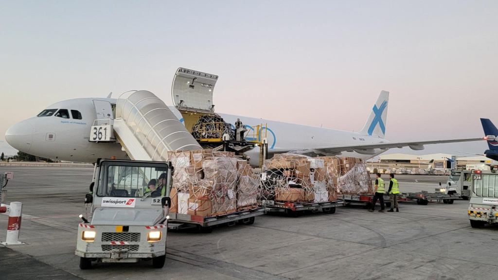 A Global X standard freighter unloads pallets of cargo at an airport.