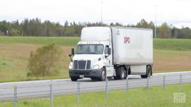 A white XPO day cab pulling a white LTL trailer on a highway