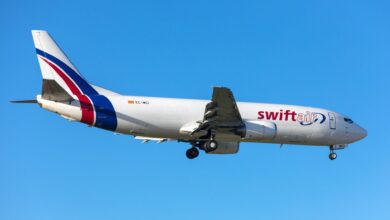 A Swiftair cargo jet flying with wheels down as it approaches an airport with wheels down.