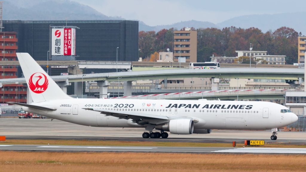 A Japan Airlines jet with red tail logo taxis to the runway.