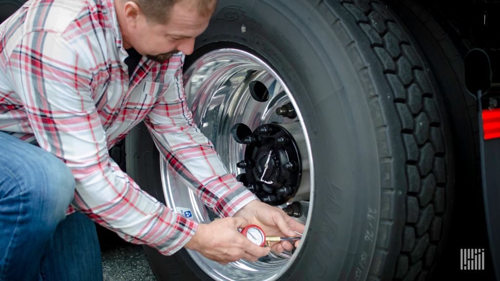 Truck driver checking tires.