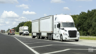 A white tractor pulling two white LTL trailers