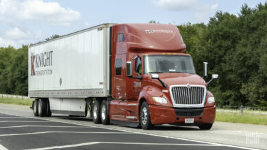 A red Knight Transportation tractor pulling a white Knight trailer on a highway