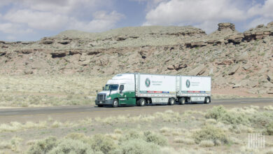 A green Old Dominion tractor pulling two LTL trailers in a desert