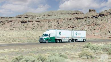A green Old Dominion tractor pulling two LTL trailers in a desert