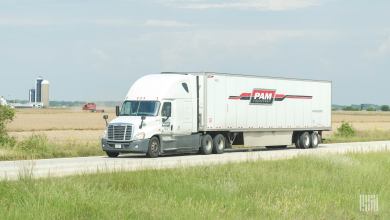 A white Pam tractor pulling a white Pam trailer on a highway
