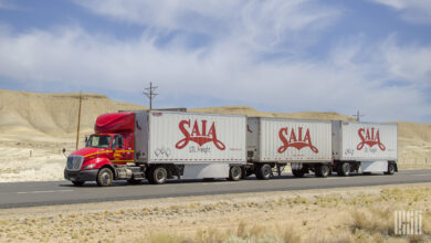 A red Saia tractor pulling three Saia trailers on a highway