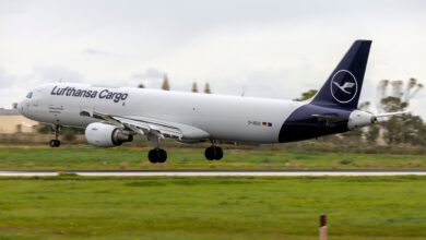 A blue-tailed Lufthansa Cargo plane touches down on runway.