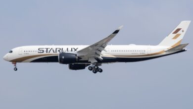 A Starlux Airlines jet approaches an airport, viewed from below.