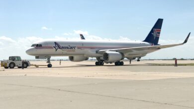 A blue-tailed Amerijet freighter sits on the tarmac on a sunny day with a small tractor by the nose.