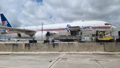 A cargo jet with the side door open is unloaded as a yellow forklift maneuvers to grab the next pallet.