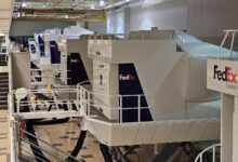 A bank of white and purple FedEx flight simulators in a building.