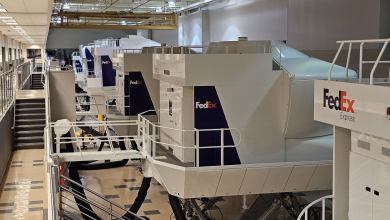 A bank of white and purple FedEx flight simulators in a building.