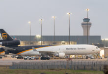 A brown-tailed UPS jet parked at an airport on a cloudy day.