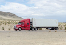 A maroon Knight Transportation tractor pulling a refrigerated Triton container