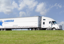 A white tractor pulling a white Landstar trailer