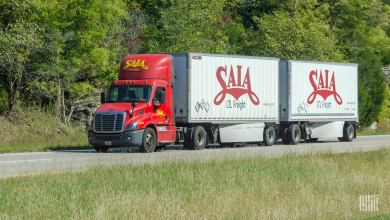 A red Saia tractor pulling two white Saia trailers