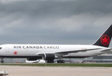 A black-tailed Air Canada Cargo jet moves on the runway on a cloudy day.